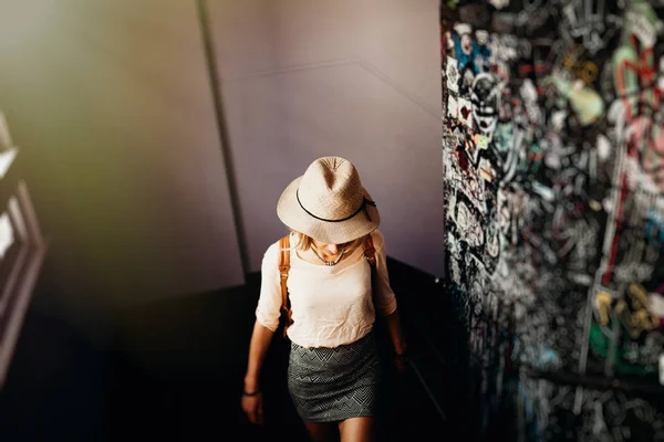 Frau mit Hut beim Treppensteigen in einem städtischen Mehrfamilienhaus. — Stockfoto