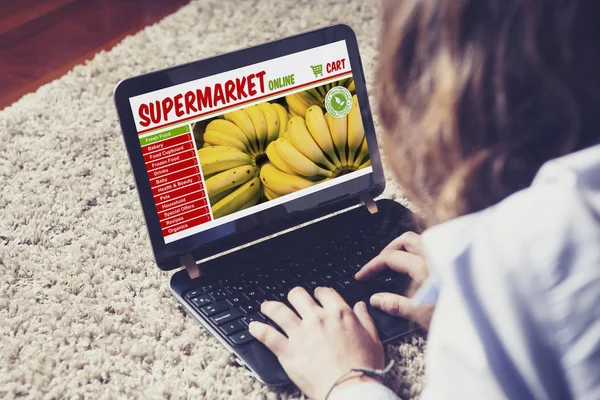 Kadının onun bakkal ile bir dizüstü bilgisayar evde internet alışveriş yapması — Stok fotoğraf