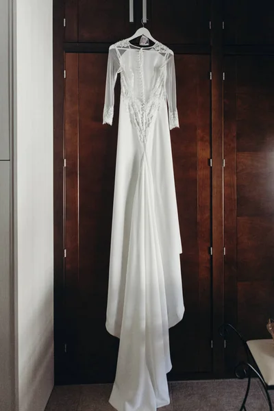 Свадебное платье висит на деревянном шкафу — стоковое фото