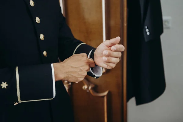 Hombre de uniforme ajustando un reloj en su muñeca . — Foto de Stock