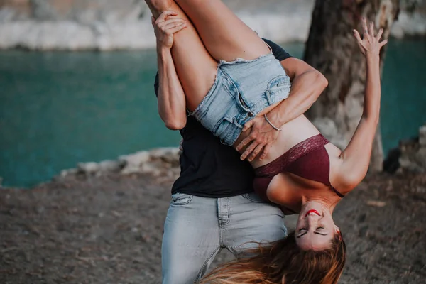 Ember tartja a barátnőjét fejjel lefelé, miközben játszik és táncol — Stock Fotó