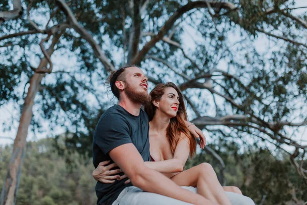 Jovem casal real sentado e abraçando enquanto olha para a natureza — Fotografia de Stock