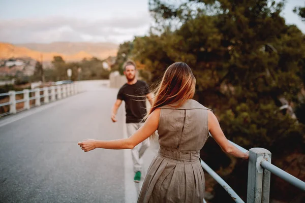 Mulher de costas dançando na frente de um homem em uma ponte em uma estrada rural — Fotografia de Stock