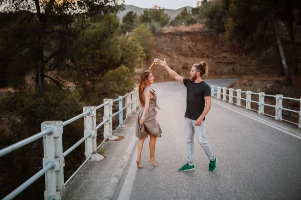 Jong koppel dansen in het midden van een weg over een brug — Stockfoto