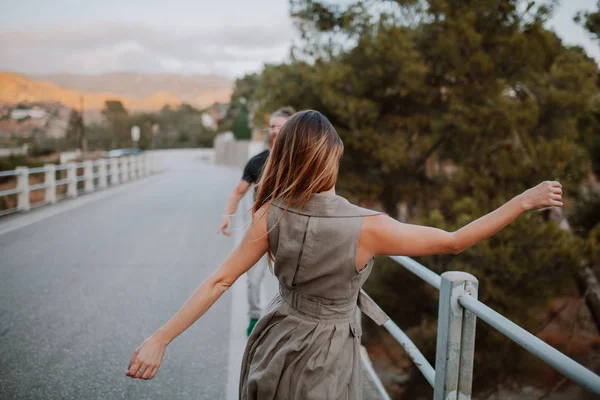 Mulher de costas dançando na frente de um homem em uma ponte em uma estrada rural — Fotografia de Stock