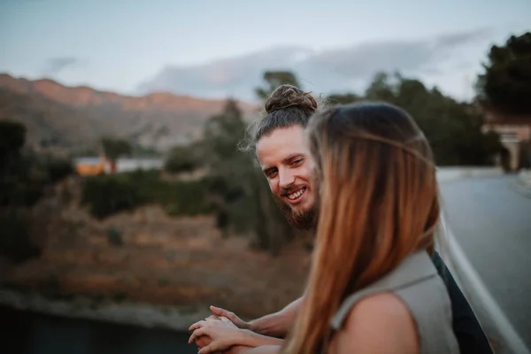 Retrato de homem barbudo sorrindo enquanto olha para sua namorada em um espaço rural — Fotografia de Stock