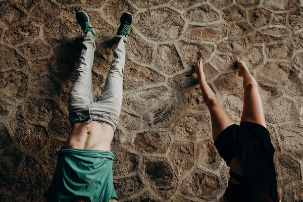 Young couple doing a handstand position in a stone wall