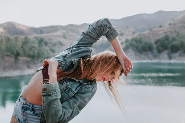 Mulher de casaco posando na natureza com um lago no fundo — Fotografia de Stock