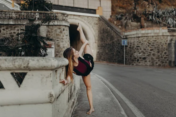 Danser verhogen been terwijl voert klassieke dans op een weg. — Stockfoto