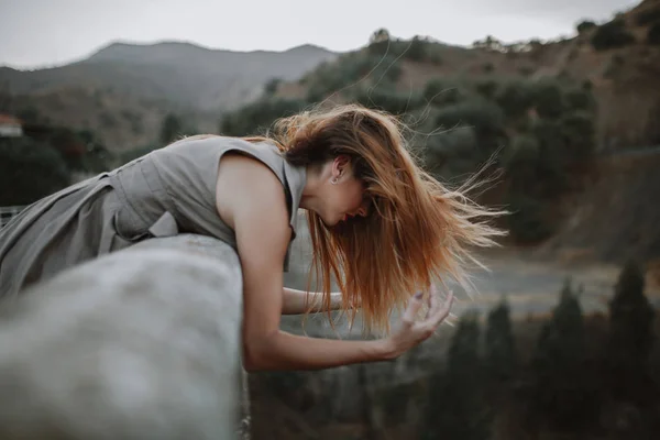 Frau sieht Natur von einer Brücke, während sie die Arme mit dem Wind bewegt — Stockfoto