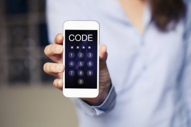 Kadın elinde tuttuğu iken bir telefon ekranında mobil giriş kodu.