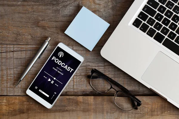 Podcast app in a phone screen placed over a wooden table at the office. — Stock Photo, Image