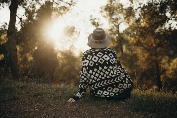 Tramonto in montagna e seduta ragazza nella sua schiena guardando la foresta e il sole . — Foto Stock