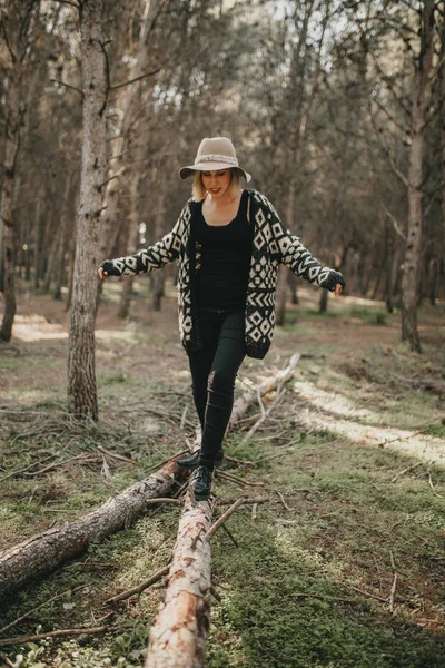 Frau in Freizeitkleidung spaziert auf umgestürztem Baumstamm im Wald — Stockfoto