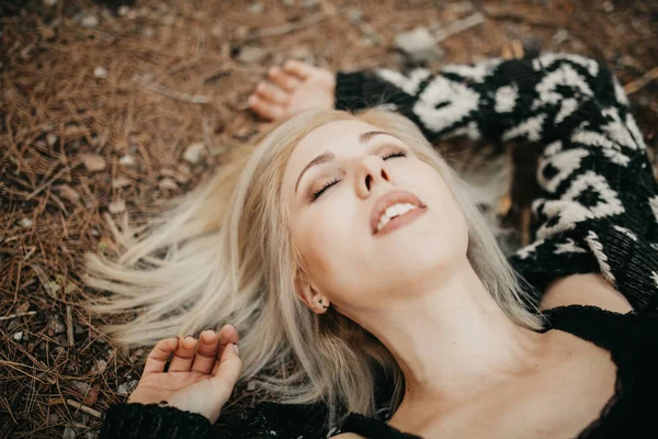 Cute blonde woman lying down on the forest ground. — Stock Photo, Image