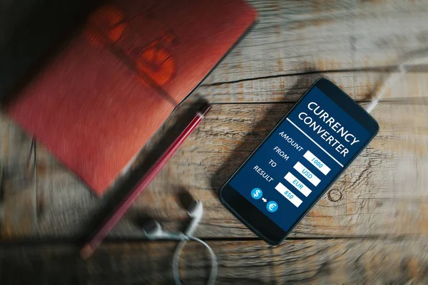Währungsumrechner mobile App in einem Handy-Bildschirm über einem Holztisch. — Stockfoto