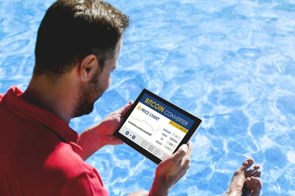 Homem negociação bitcoin preço em um site conversor bitcoin com um tablet, enquanto sentado ao ar livre . — Fotografia de Stock