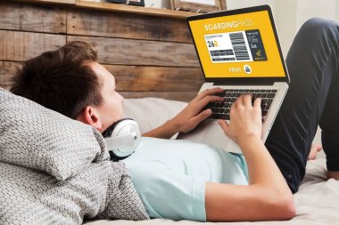 Biniş kartı evde yazdırmak için bir dizüstü bilgisayar kullanan adam uçuş.