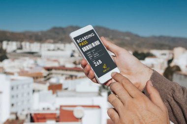 Bir cep telefonu ekran dijital biniş kartı ile elinde tutan adam.