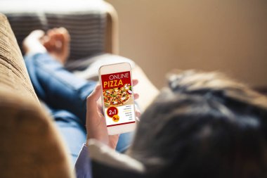 Pizza dükkanı Web sitesi ile bir cep telefonu ekran tutan kadın.