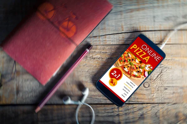 Ahşap bir masa üzerinde bir cep telefonu ekran üzerinde satır pizza dükkanı. — Stok fotoğraf