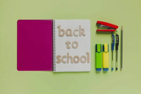 Back to school letters on a notebook with other stuff and green background — Stock Photo, Image