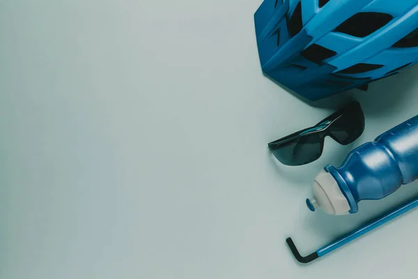 Fahrradhelm, Brille, Wasserflasche und Inbuswerkzeug mit Kopierraum, auf blauem Hintergrund. — Stockfoto