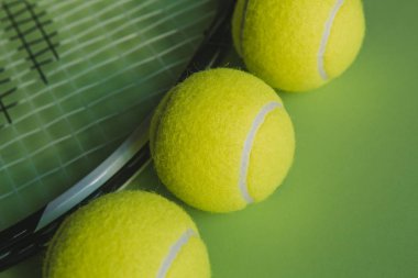 Makro görünümü bir tenis raketi ve üç tenis topları yeşil zemin üzerine.