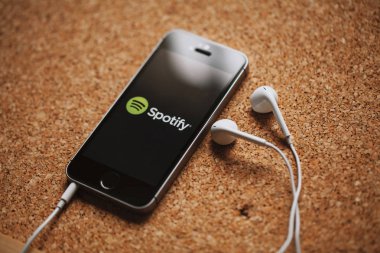 Malaga, İspanya - 5 Mart 2018: cep telefonu Spotify logolu bir mantar panelde yerleştirilmiş ekran ve beyaz kulaklık.