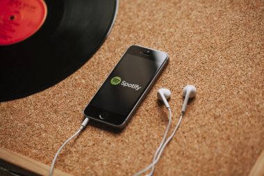 Malaga, İspanya - 5 Mart 2018: cep telefonu ekranında, beyaz kulaklık ve vinil disk Spotify logolu bir mantar panelde yerleştirilmiş.