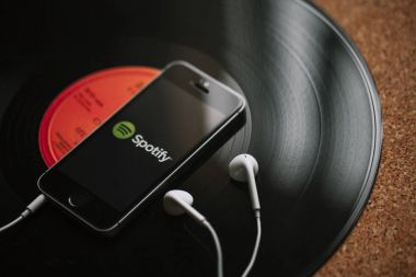 Malaga, İspanya - 5 Mart 2018: cep telefonu siyah vinil kayıt üzerinde ekran ve beyaz kulaklık Spotify müzik Servisi.
