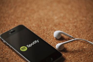 Malaga, İspanya - 5 Mart 2018: cep telefonu Spotify logolu bir mantar panelde yerleştirilmiş ekran ve beyaz kulaklık.
