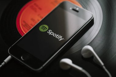 Malaga, İspanya - 5 Mart 2018: cep telefonu siyah vinil kayıt üzerinde ekran ve beyaz kulaklık Spotify müzik Servisi.
