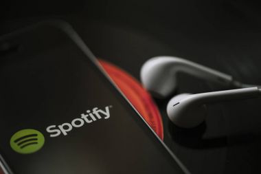 Malaga, İspanya - 5 Mart 2018: cep telefonu siyah vinil kayıt üzerinde ekran ve beyaz kulaklık Spotify müzik Servisi.