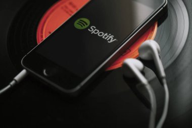 Malaga, İspanya - 5 Mart 2018: cep telefonu siyah vinil kayıt üzerinde ekran ve beyaz kulaklık Spotify müzik Servisi.