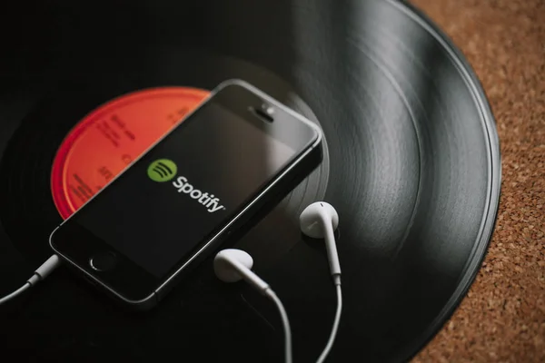 MALAGA, SPAIN - MARCH 5, 2018: Mobile phone with Spotify Music service in the screen and white earphones on a black vinyl record. — Stock Photo, Image