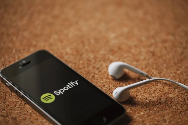 Spotify-Musikstreamingdienst auf Smartphone-Bildschirm und weißen Kopfhörern. — Stockbild Malaga, spanien - 5. märz 2018: handy mit spotify-logo auf dem bildschirm und weißen kopfhörern, platziert auf einer korkplatte. — Stockfoto