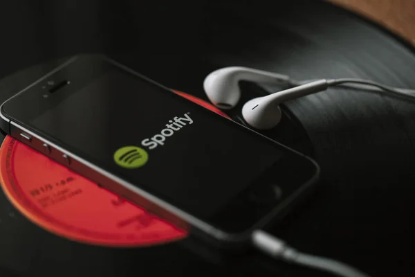 Malaga, İspanya - 5 Mart 2018: cep telefonu siyah vinil kayıt üzerinde ekran ve beyaz kulaklık Spotify müzik Servisi.