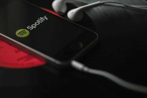 Spotify-Musikstreamingdienst auf Smartphone-Bildschirm und weißen Kopfhörern. — Stockbild Malaga, spanien - 5. märz 2018: handy mit spotify-musik-service auf dem bildschirm und weißen kopfhörern auf schwarzer schallplatte. — Stockfoto