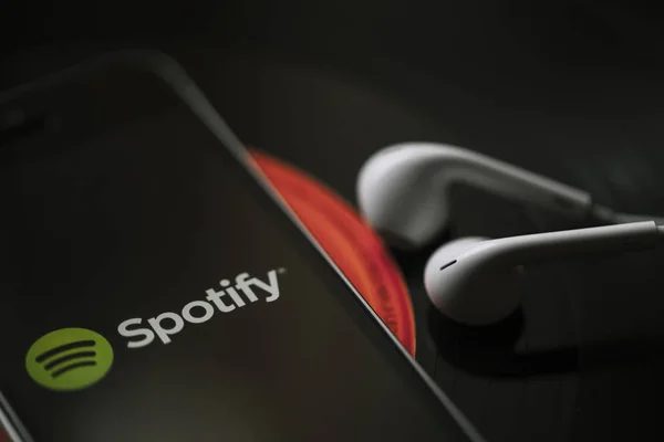 MALAGA, ESPAÑA - 5 DE MARZO DE 2018: Teléfono móvil con servicio Spotify Music en pantalla y auriculares blancos en un disco de vinilo negro . —  Fotos de Stock