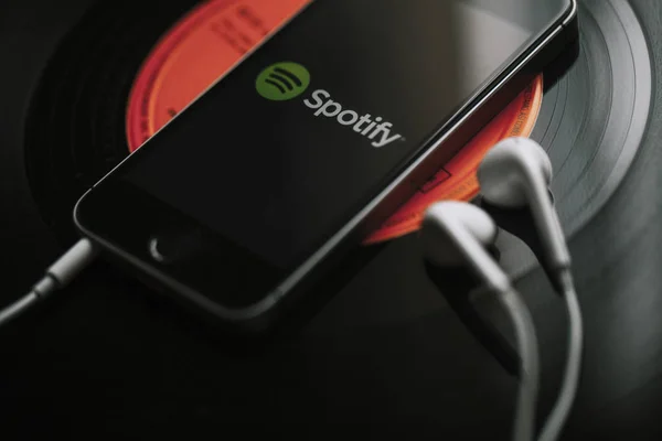 Malaga, İspanya - 5 Mart 2018: cep telefonu siyah vinil kayıt üzerinde ekran ve beyaz kulaklık Spotify müzik Servisi.