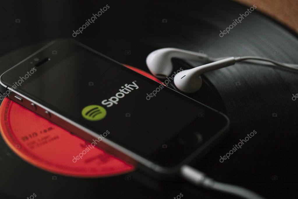 Spotify music streaming service on a smartphone screen and white earphones.