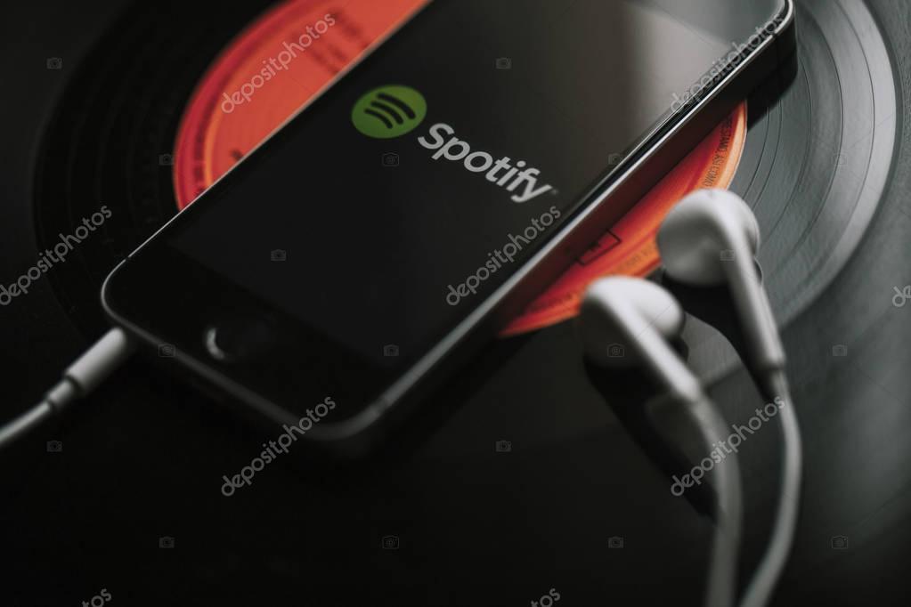 Spotify music streaming service on a smartphone screen and white earphones.