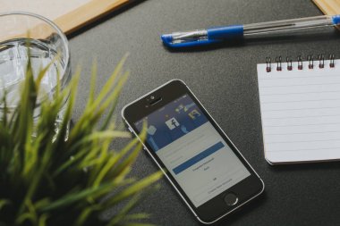 Malaga, İspanya - 6 Mart 2018: cep telefonu ile Facebook app ekranda siyah masa başı işleri yakın içinde.