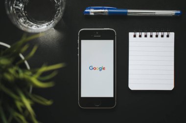 Malaga, İspanya - 6 Mart 2018: Google app bir siyah çalışma alanı diğer office malzeme ile yerleştirilen bir cep telefonu ekranında,.