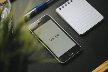Malaga, İspanya - 6 Mart 2018: Google app bir siyah çalışma alanı diğer office malzeme ile yerleştirilen bir cep telefonu ekranında,.