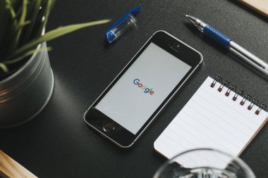 Malaga, İspanya - 6 Mart 2018: Google app bir siyah çalışma alanı diğer office malzeme ile yerleştirilen bir cep telefonu ekranında,.