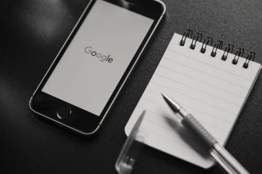 Malaga, İspanya - 6 Mart 2018: siyah beyaz görüntü Google App bir siyah çalışma alanı diğer office malzeme ile yerleştirilen bir cep telefonu ekranında,.