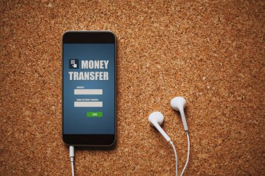 Cep telefonu ile para transferi app ekran, beyaz kulaklık ve bir mantar panel kopya alanı.