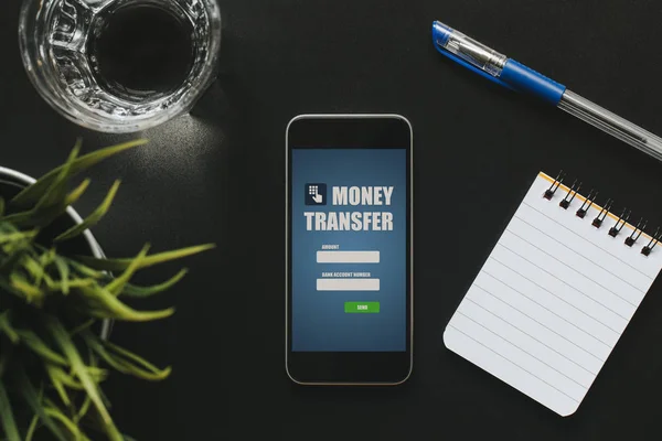 Vista frontal de la aplicación de transferencia de dinero en una pantalla de teléfono móvil sobre una mesa de negocios negra . —  Fotos de Stock